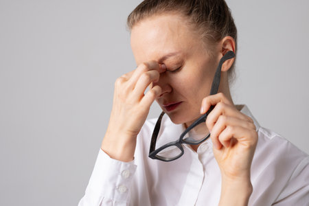 Woman takes off her glasses and holds her eyes in pain, concept of optics, glasses selection and vision problemsの写真素材