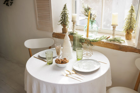 Cozy Christmas setting with a round table near the window in Scandinavian style, in the background...