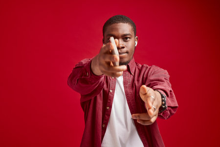 emotional man african appearance with phone in hands technology communication joy, isolated on red background studio portraitの写真素材