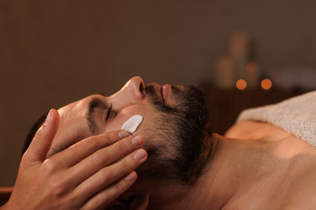 Cosmetician applying cosmetic cream of man in spa. body careの写真素材