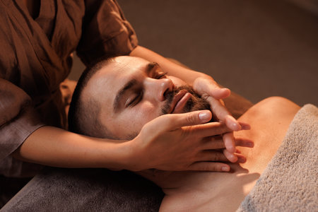 Therapeutic Facial Massage Targeting Facial Muscles for Relaxation and Skin Revitalization in a Calm Spa Environment Focused on Rejuvenation and Well-being for Menの写真素材