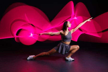 young girl athlete doing sports in neon light on dark background, concept modern sports trainingの写真素材