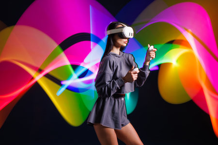 VR, AR, MR, XR Future technologies. Neon. Young girl in VR glasses in neon doing sports and playing a game. Concept of modern gadgets and technologiesの写真素材