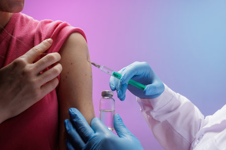 Close-up of a healthcare professional applying a bandage after a vaccination, with a syringe in hand, ensuring post-injection care and patient safety.の写真素材