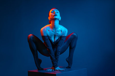 Confident female dancer in black bodysuit striking bold pose under dramatic red and blue neon...