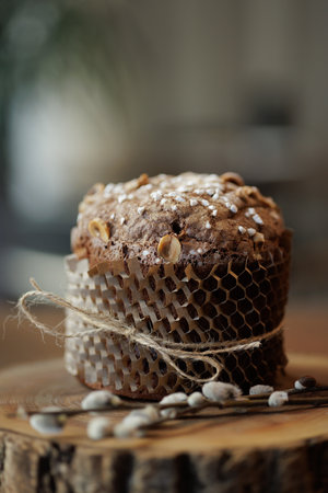 Artisan chocolate Easter cake with hazelnuts and sugar topping, wrapped in eco paper on rustic wood slab.の写真素材