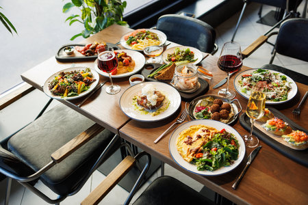 Top view of a festive restaurant table with a wide variety of gourmet dishes, salads, and glasses of wine.の写真素材