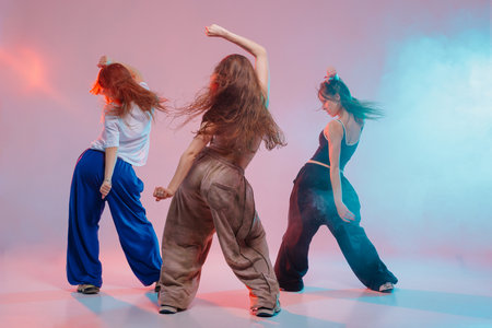 Group of young women performing jazz funk dance with expressive moves in a vibrant studio with colorful lighting and energyの写真素材