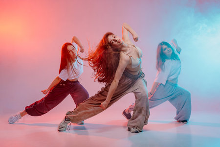 Energetic group of young women performing jazz funk dance with expressive poses in a vibrant studio with modern lightingの写真素材