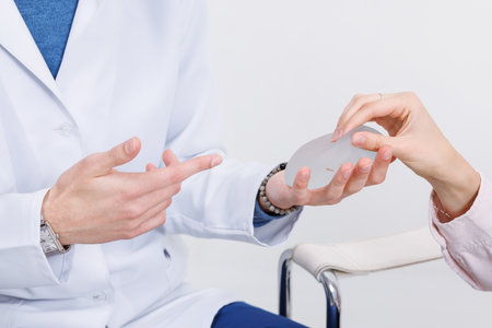 Plastic surgeon showing breast implant and explaining mammoplasty augmentation and correction to...
