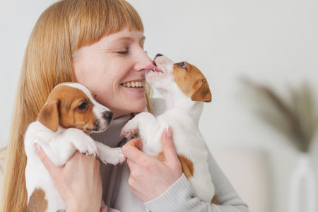 Woman smiling as puppy licks her nose shows love for animals, pet care, affection and joyful bonding at home.の写真素材