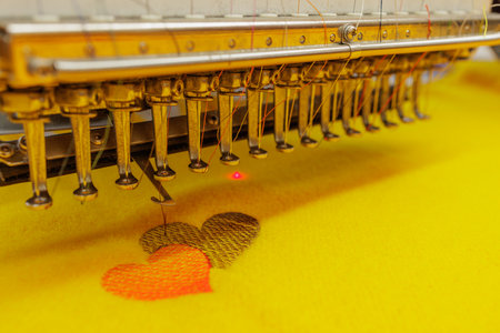 Automated embroidery machine creating colorful heart pattern on fabric, symbolizing love, creativity, and textile design process.の写真素材