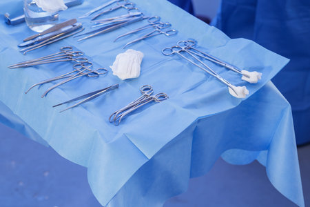 Clean instrument table with clamps, scissors and gauze on blue drape, illustrating aseptic...