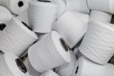 Clean white yarn cones stacked for textile production in a factory ready for spinning or weaving...