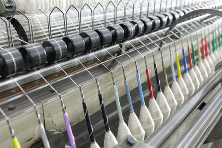 Closeup of warp yarn threads guided through loom system, illustrating precision textile weaving...