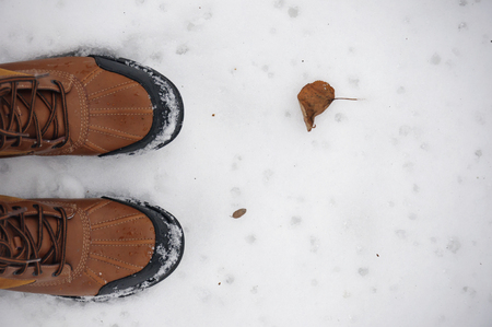 Red boots and dry leaf on the snowの写真素材