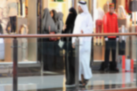 Arab sheikhs men and their wives and families in a mall make a purchase, Dubai, people go to the mall, market, blurred for backgroundの写真素材