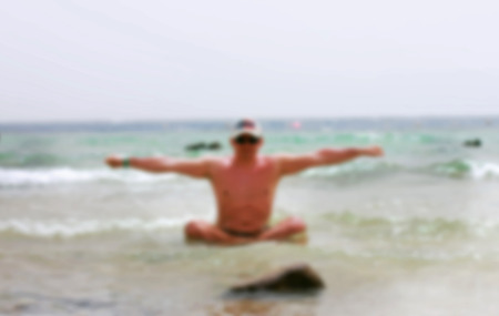 a man on the beach doing yoga, blurredの写真素材