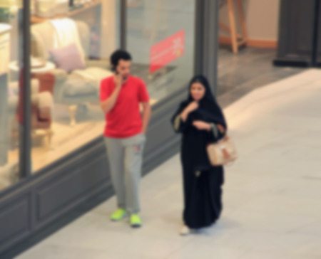 Arab sheikhs men and their wives and families in a mall make a purchase, Dubai, people go to the mall, market, blurred for backgroundの写真素材