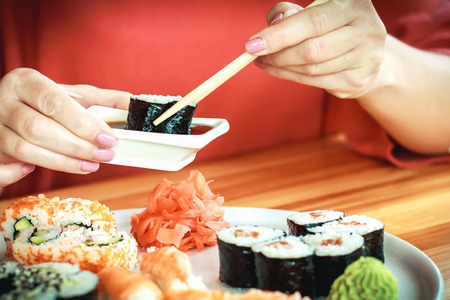 The best sushi rolls, Japanese cuisine. Various delicious sushi rolls. The hand is dipped in soy sauce, delicious food.の写真素材