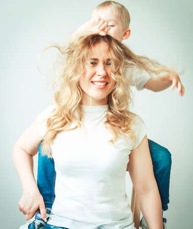small boy indulges with mother's hair, having fun playing mother and son, happy family, selective focusの写真素材