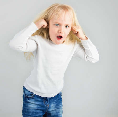 little girl teasing, showing tongue and doing face, on white background, soft focusの写真素材