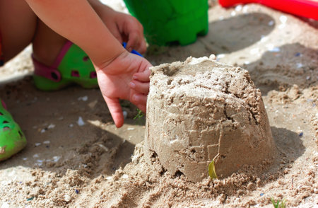 The child's hands build a castle of sand. In the summer vacation on the sea. Summer vacationsの写真素材