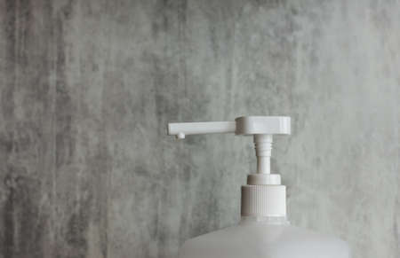 spray dispenser white on a gray background in the foreground green leaves of a flower. cosmetics concept. Cosmetic containers. container for the disinfector. Sprayer.の写真素材