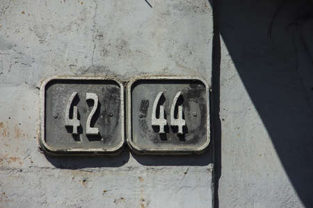 old gray wall with house numbering. numbering on the old house. Apartment number 42 and 44の写真素材