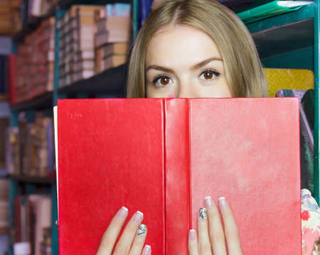 the girl at the library with books expressing emotion surprise stack of books holdingの写真素材