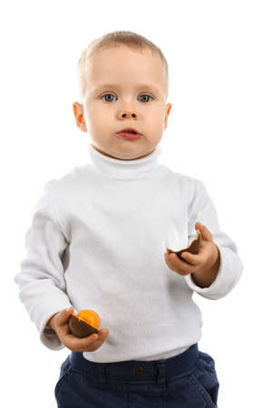 Little boy eating a delicious chocolate Easter egg on white backgroundの写真素材