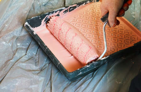 rasit hand wall paint using a paint roller while working indoors, make repairsr