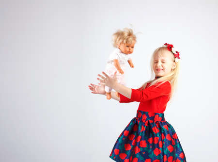 Little happy girl playing a doll, on a white backgroundの写真素材