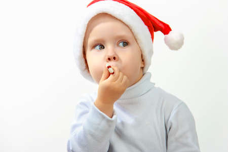 Little happy boy in cap of santa claus, on white backgroundの写真素材