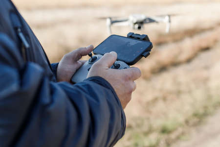 the hands of the male pilot are holding the remote control of the drone. Drone video filming.の写真素材