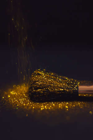 texture of gold glitter on the makeup brush and design. We have a black background. Selective Focus...