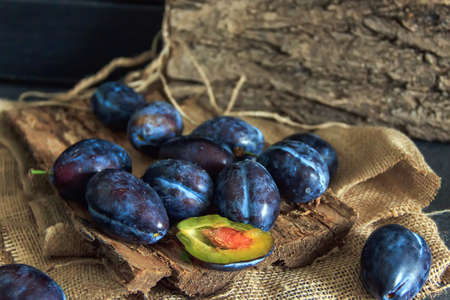 Garden plums on the table. Autumn harvest. Blue feathers. Fresh feathers on a wooden surface. Fresh plums on a wooden table background. Food Photo - Pictureの写真素材