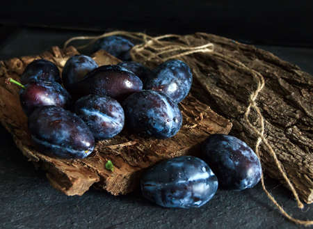 Garden plums on the table. Autumn harvest. Blue feathers. Fresh feathers on a wooden surface. Fresh plums on a wooden table background. Food Photo - Pictureの写真素材