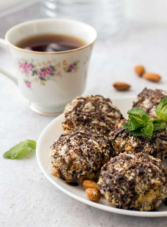 Useful homemade almond cake with coconut flakes on a light background and a cup of tea, copy space -...