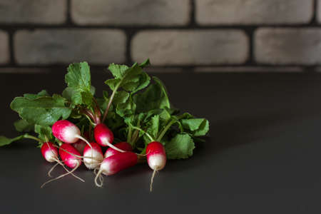 Fresh red radish on a dark table. Growing organic vegetables. A bunch of raw fresh radishes on a dark background ready to eat. Raw foods. food photography - Imageの素材 [FY310190656204]