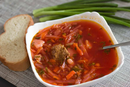 Ukrainian beetroot soup - borscht in a white bowl on the kitchen table. Delicious beet soup. Fresh borsch on the table surrounded by products - Imageの写真素材