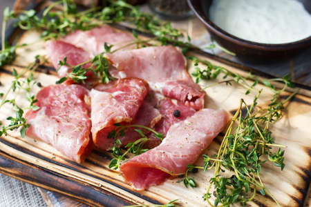 Delicious flavorful ham sliced ââinto strips on a wooden background with spices and fresh thyme. A serving of low-fat succulent farm meat pork. meat product. Food Photography - Imageの写真素材