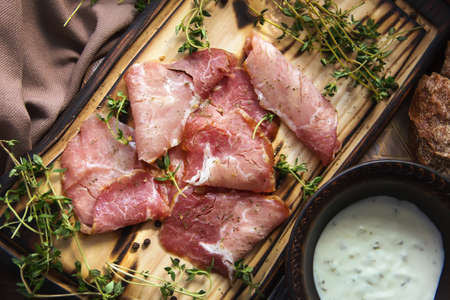 delicious pork bacon sliced ââinto strips on a wooden background with spices and fresh thyme. A serving of low-fat succulent farm meat pork. Food Photography - Imageの写真素材