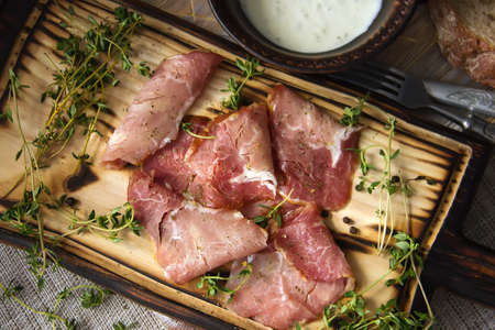Delicious flavorful ham sliced ââinto strips on a wooden background with spices and fresh thyme. A serving of low-fat succulent farm meat pork. meat product. Food Photography - Imageの写真素材