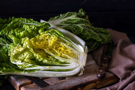 Fresh Chinese cabbage in a cut on a dark wooden background. Diet nutrition. Vegetables and fruits. Dark Food Photographyの写真素材