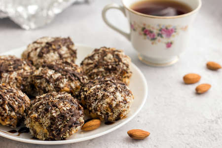 Useful homemade almond cake with coconut flakes on a light background and a cup of tea, copy space - Imageの写真素材