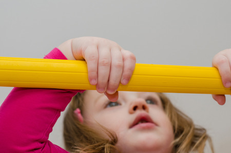 little girl hanging on horizontal barの写真素材