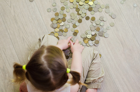 little girl counting and playing with coinsの写真素材