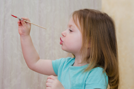 little girl draws with a brush and paintsの写真素材