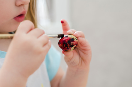 the child paint easter eggs by brush and red paintsの写真素材